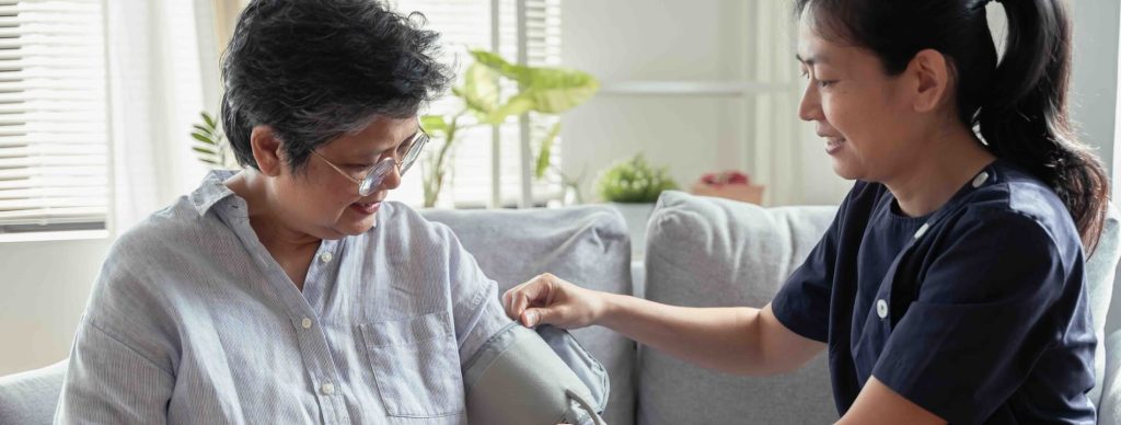 Home Health Aide taking blood pressure of her patient in her home.