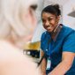 Nurse using stethoscope on elderly patient.