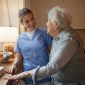 Nurse helping elderly woman with care at home.