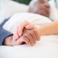 Person holding hands with a patient on hospice.
